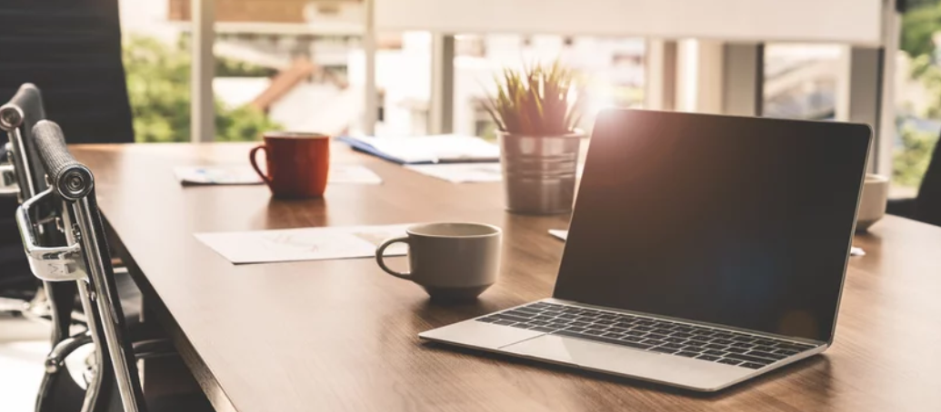 a laptop on a wooden table with a cup of coffee in front of it. 